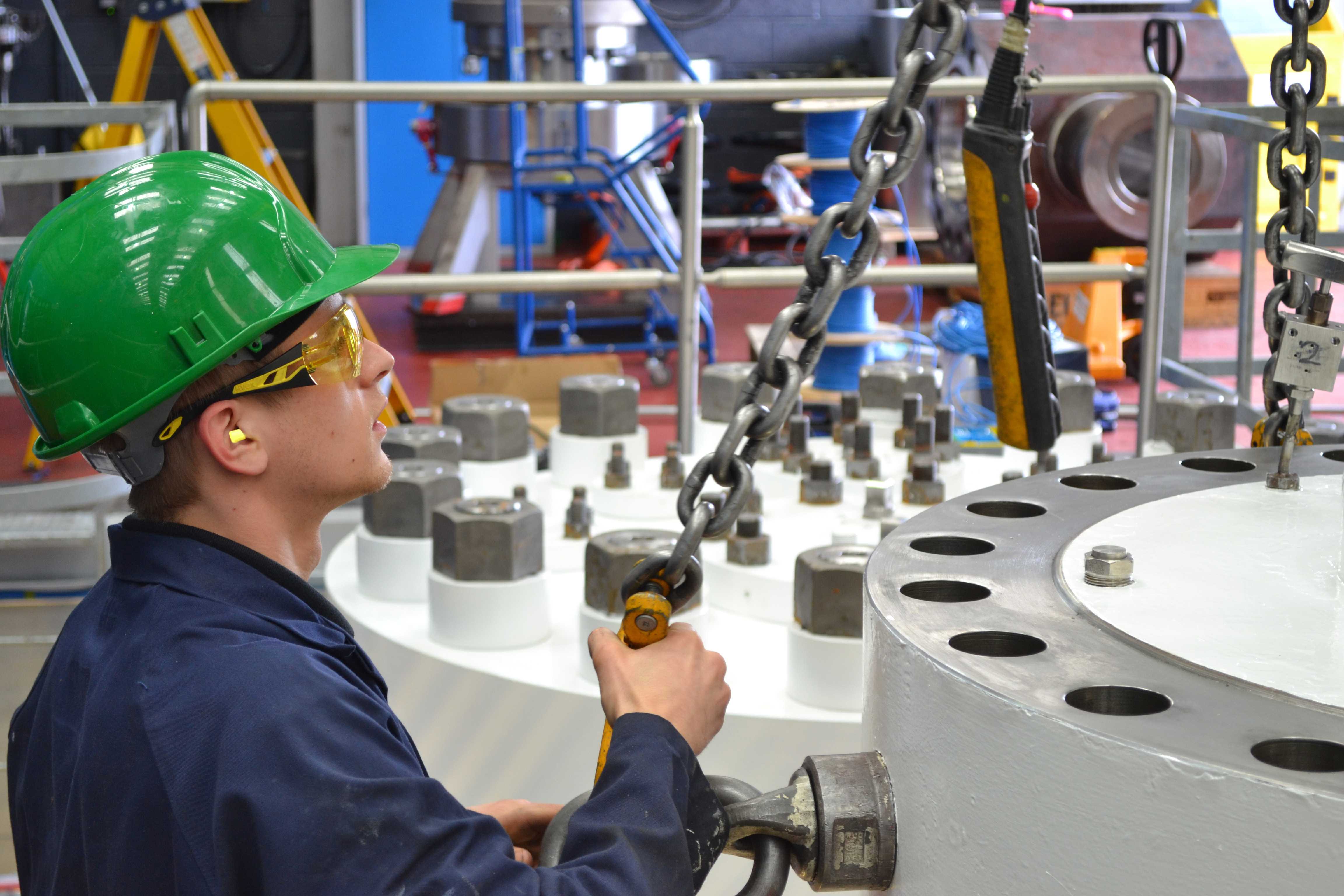 Man wearing green hard hat handling valve